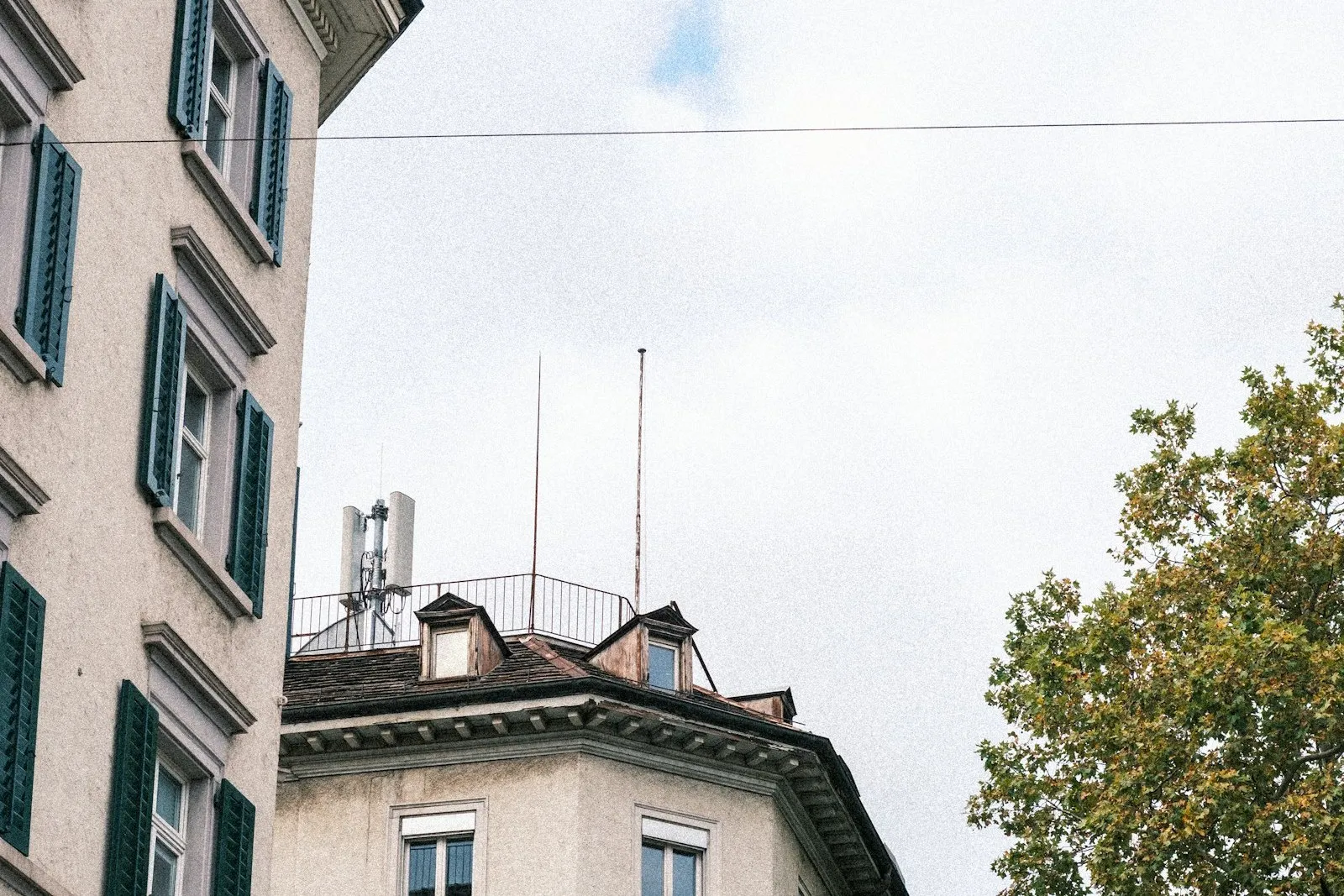 Fassade eines älteren städtischen Wohnhauses mit hohen Fenstern und grünen Fensterläden.