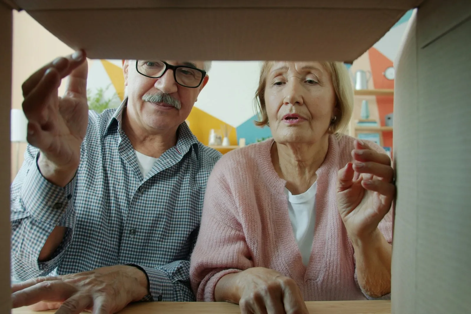 Ein älteres Paar blickt gemeinsam in einen geöffneten Umzugskarton.